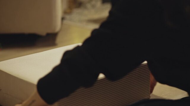 A Wrapped Christmas Gift is Gently Lifted by its Twine, Capturing a Simple, Cozy Holiday Moment - Close Up