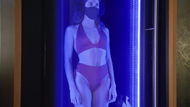 Woman stepping into a cryotherapy machine at extreme cold temperature, visible breath and chills on skin. Intense wellness treatment, recovery moment, and premium health lifestyle atmosphere.