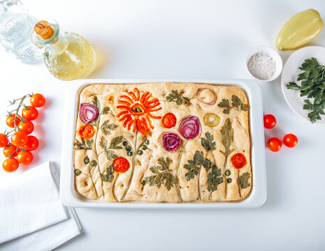 Floral focaccia bread with tomato and herb art, flatlay
