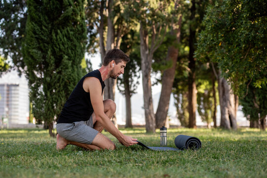 Man preparing for yoga on mat in park during workout