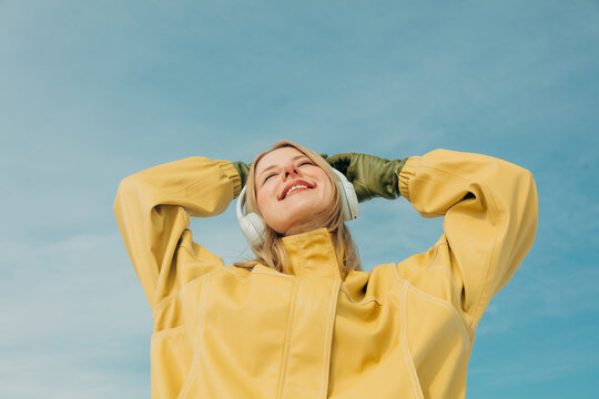 Woman enjoying music outdoors in yellow jacket