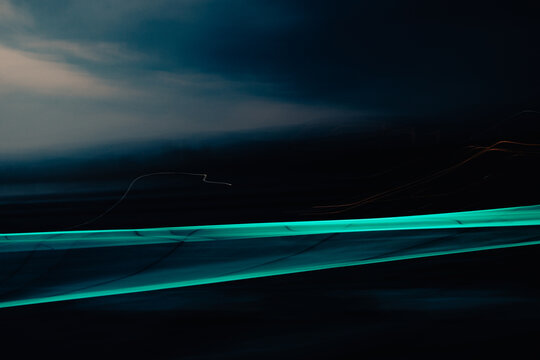 Abstract teal light streak with motion blur on dark