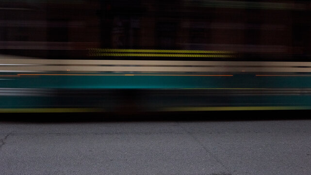 Motion blurred tram speeding past urban street at dusk