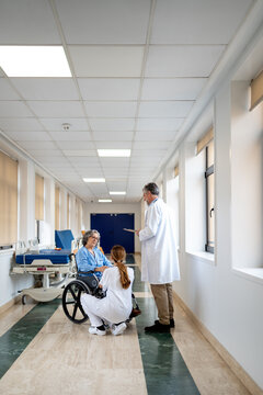 Doctors conversing with patient in hospital corridor