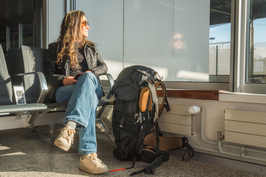 Woman waiting in A sunlit train station with backpack