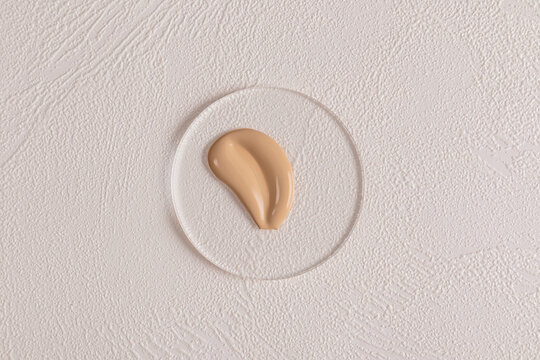 Beige cosmetic foundation on textured white surface