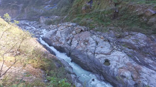 Mandakini River Rushing Through Rocky Mountain Valley with Distant Rambada bridge, Kedarnath Trek, India