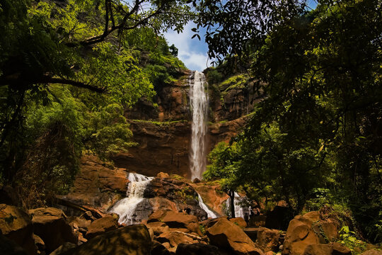 Majestic Curug Cikanteh waterfall in Ciletuh Geopark, Sukabumi. Powerful water cascading down brown rocky cliffs surrounded by lush jungle.