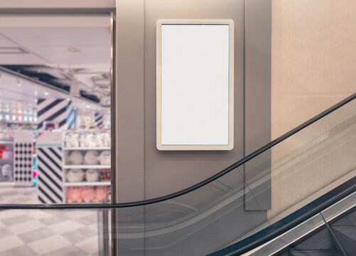 Blank shopping mall sign beside escalator in store