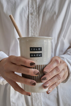 Hands with brown manicure holding COLD BREW mug
