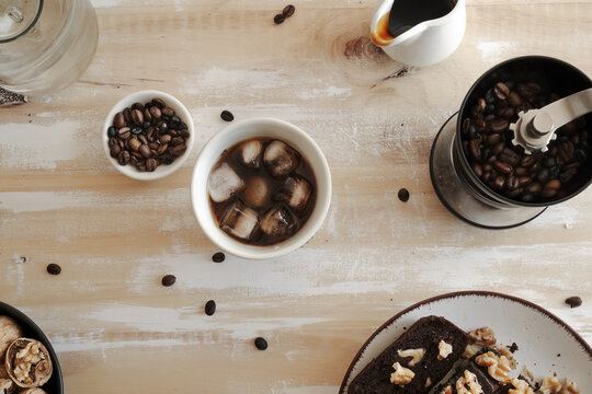 Iced coffee with grinder, beans and walnuts on table