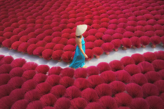 Woman walking through vibrant incense bundles