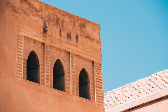 Moroccan riad facade with arched windows under blue sky