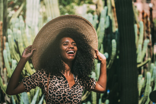 Cheerful woman in straw hat enjoying lush garden sunshine