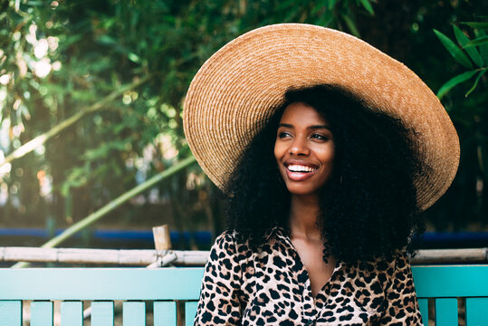 Woman in straw hat relaxing on bench in lush garden
