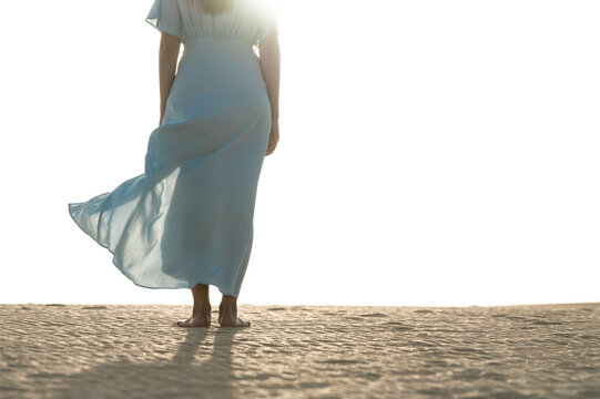 Barefoot woman in dress facing Corralejo dunes, Spain