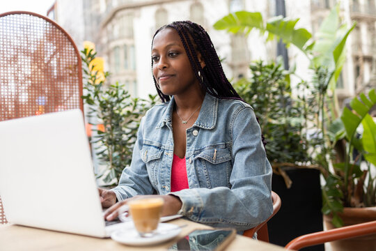 Woman enjoying coffee while working on laptop