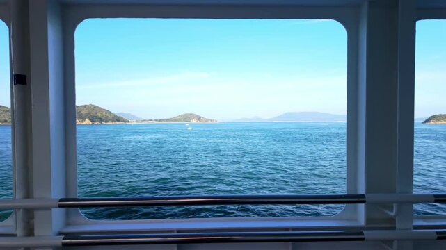 View of blue sea and distant islands through a ferry window