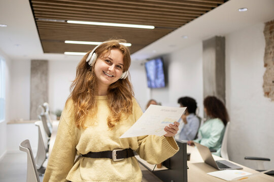 Smiling coworker with headset holding document in office