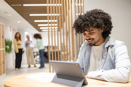 Latin man using tablet in coworking office teamwork scene
