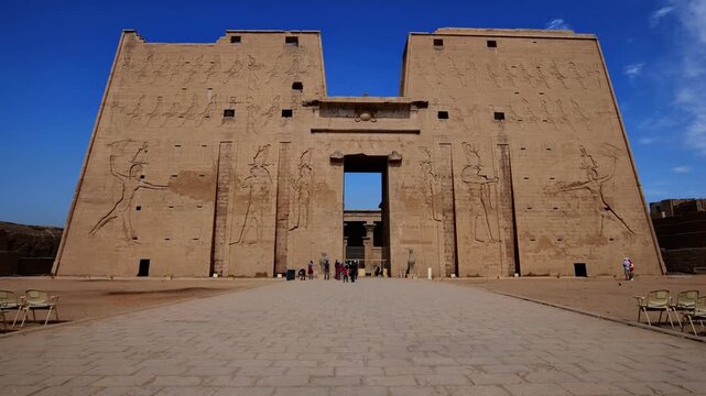 Massive pylon facade of Edfu Temple with giant pharaoh reliefs and central gateway, Egypt. Best preserved ancient Egyptian temple exterior for travel and history projects.