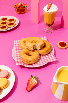 Assorted desserts on vibrant pink background, flat lay