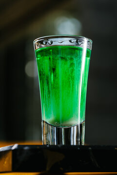 Green absinthe shot with anise notes in a clear glass