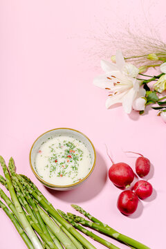 Cold okroshka with kefir, asparagus and radish on pink