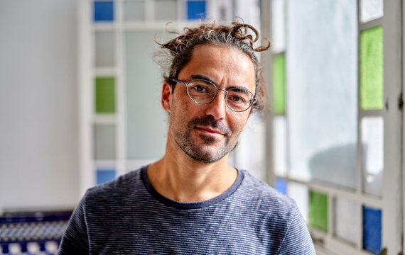 Working from home, a man smiles while in a room with colorful windows