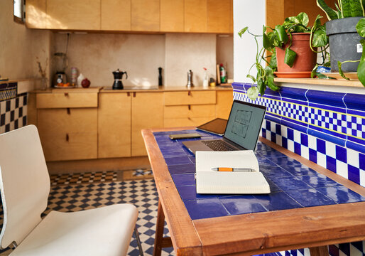 Work from home setup in a kitchen with a laptop and notepad