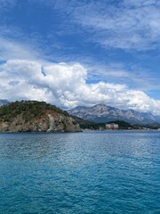 Obraz premium Panoramic view of the Taurus mountain range. View from afar of the village of Camyuva in Turkey. Calm Mediterranean sea, blue water. Mountains in the clouds.