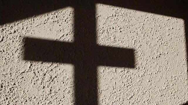 Simple cross shadow cast on textured wall, dramatic lighting, minimal concept, symbolic and modern, clean commercial look&rdquo;