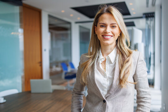 Confident businesswoman smiling in a modern office, representing professional success and corporate leadership