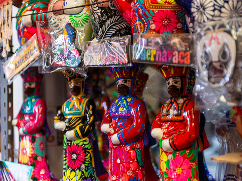 Colorful Handmade Clay Figurines in Traditional Attire Displayed on Wooden Surface. Chinelo.