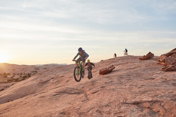 Obraz premium People, mountain bike and cycling with sunset in wilderness for extreme sport or fitness together. Active, cyclist or group of friends riding with bicycle on dirt trail for outdoor challenge in dunes
