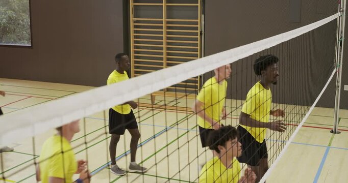 Diverse male teammates in yellow shirts starting drill, walking to net and practicing blocks