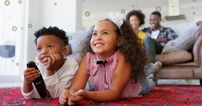Boy pressing remote while kids lying on red rug watching media, bubble overlay drifting over kids
