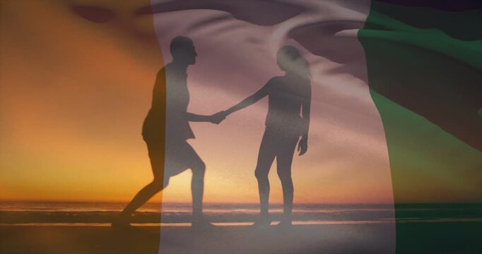 Man kneeling proposing wedding woman accepting ring lifting on beach semi-transparent flag waving