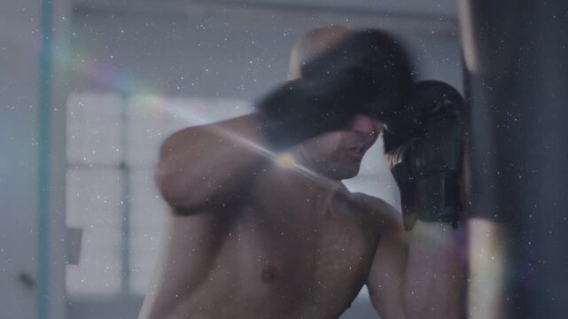 Male boxer starting tightguard jab combo on heavy bag for training, gloves flashing lensflare dust