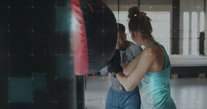 Vertical video: Coaching coach cueing trainee teal tank doing jabs for form at gym with bag, gloves