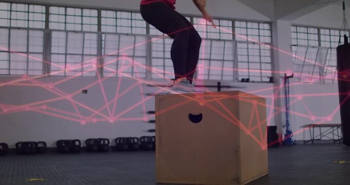 Female athlete building power on plyo box in gym, arm swing initiating takeoff, pink overlay moving