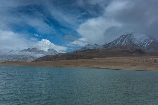 A wide view of Baisha Lake with turquoise waters and distant snow-capped mountains on the Pamir Plateau.scenic high-altitude lake is along the KKH near the China-Pakistan border in Xinjiang, China