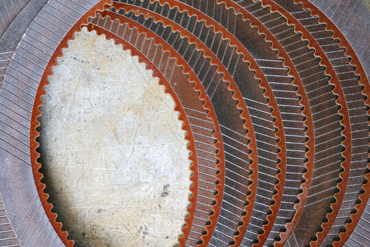 A set of brand-new, stacked automatic transmission clutch friction discs featuring detailed cross-hatch surface patterns, serrated inner splines, and a reddish-brown composite material.