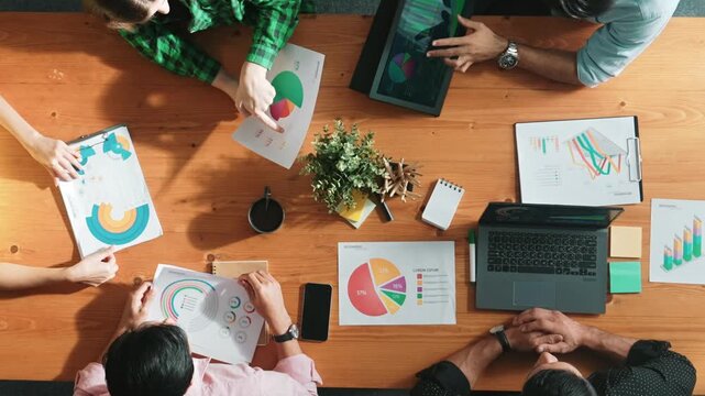 Top view of project manager using tablet to analyze data and financial chart while marketing team working together to brainstorm marketing campaign or planning strategy at meeting room. Convocation.