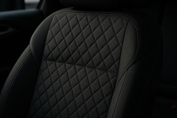 Naklejka premium Close-up of a dark grey quilted car seat with diamond pattern and contrasting stitching. Modern, textured automotive interior detail for luxury and comfort concepts.