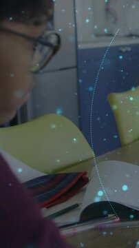 Studying pupil in purple-top specs leaning at home-table book striped-case blue overlay, copy space