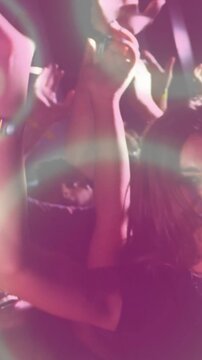 Vertical video: Woman dancing as bass causing pink rings crossing face and crowd raising arms