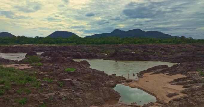 An aerial view shows a sandy beach next to Li Phi Waterfall. a part of the Mekong River in Laos. surrounded by lush greenery, making it a premier natural attraction in the Si Phan Don region.