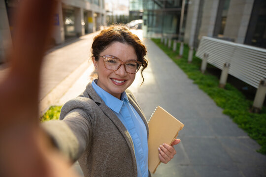 Happy business woman taking selfie outdoors in city
