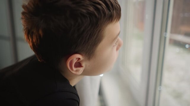 Pensive young observer. Boy contemplates on frosty winter day. Thoughtful youth gazes out on chilly winter morning scene. Young boy with serious look reflects quietly as winter morning begins